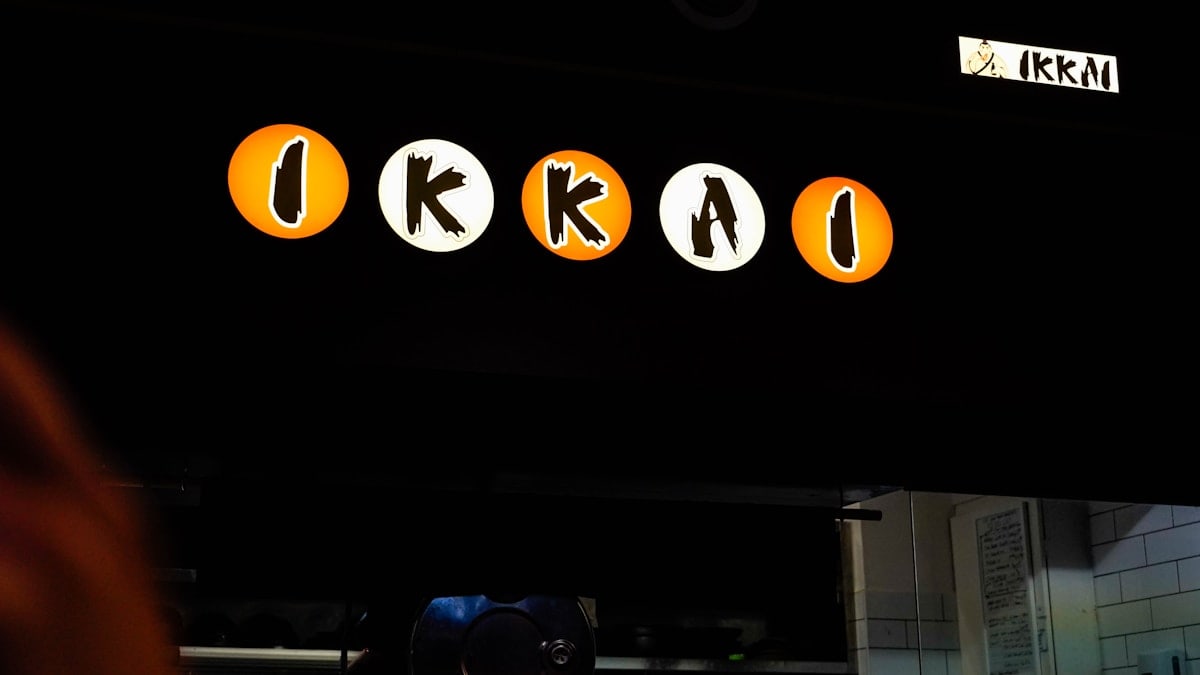 a person standing in front of a sign for a restaurant