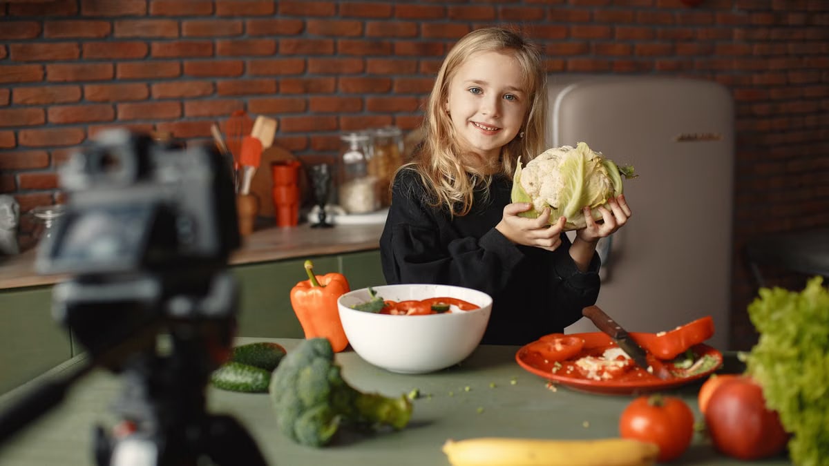 A young girl holds a cauliflower while making a fresh vegetable salad in a kitchen.